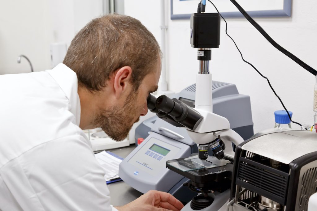 Ricercatore al microscopio nel laboratorio Aliplast