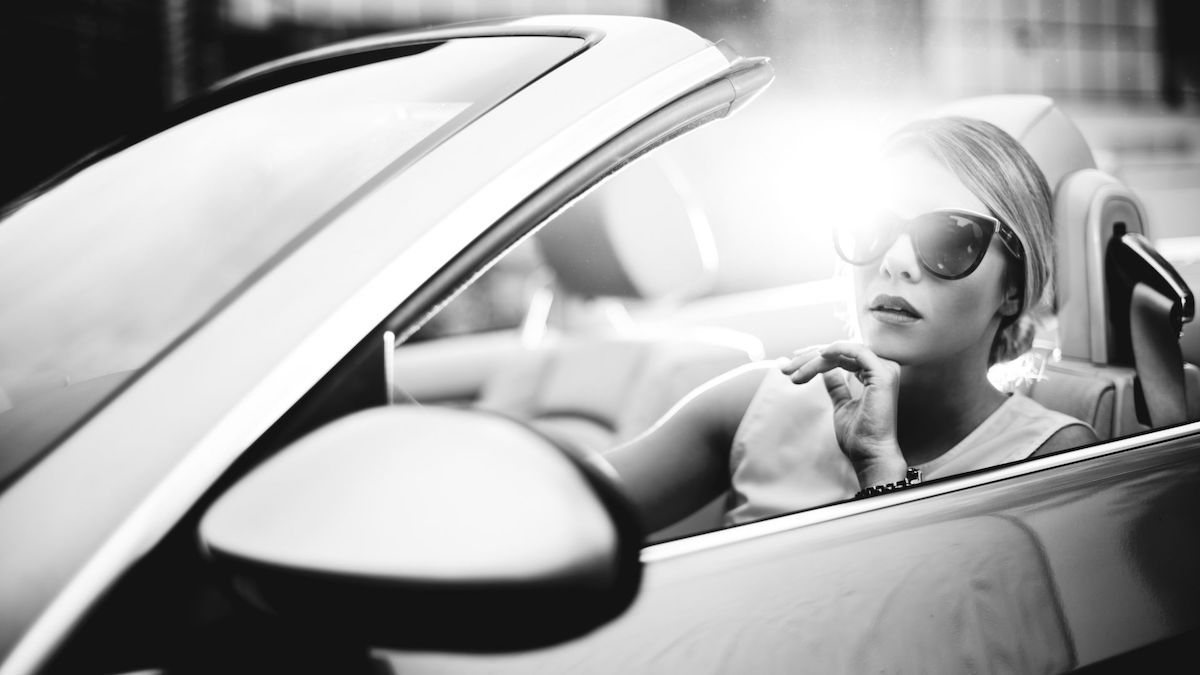 Donna elegante su auto di lusso, immagine simboleggia il mercato dei beni di lusso